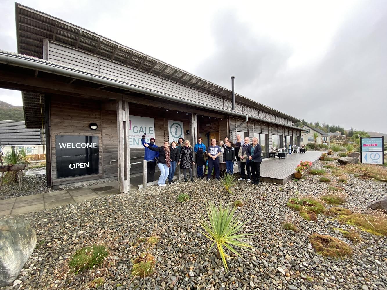 A photo of the Gairloch and Loch Ewe Active Community Enterprise building. Standing outside is staff waving to the camera.